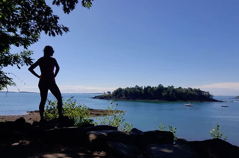 a woman looks over Maine's coast toward an island
