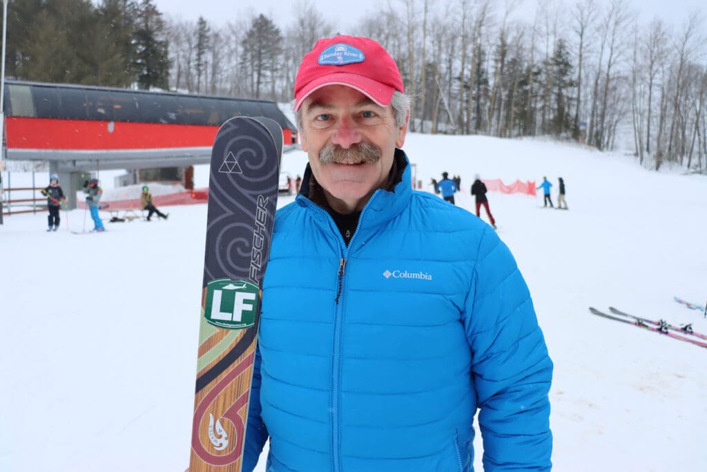 Dave Coughlan stands, holding his skis, at Sunday River in March 2023.