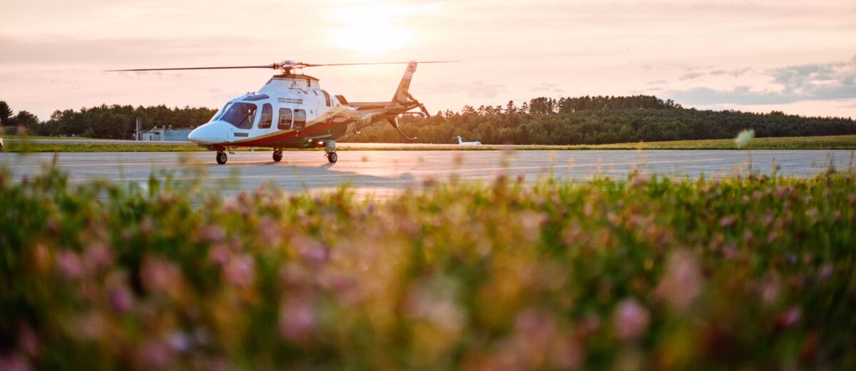 A LifeFlight helicopter sits on the runway at sunset.