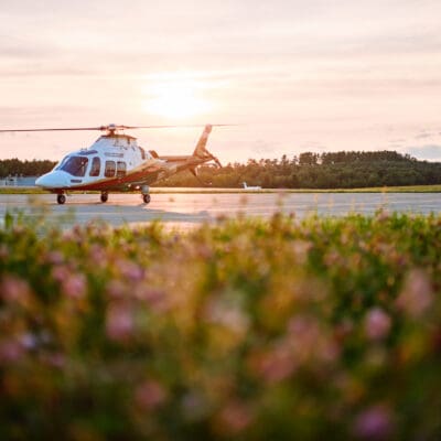 A LifeFlight helicopter sits on the runway at sunset.