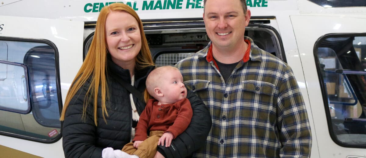 Oliver White and his parents in front of a helicopter.