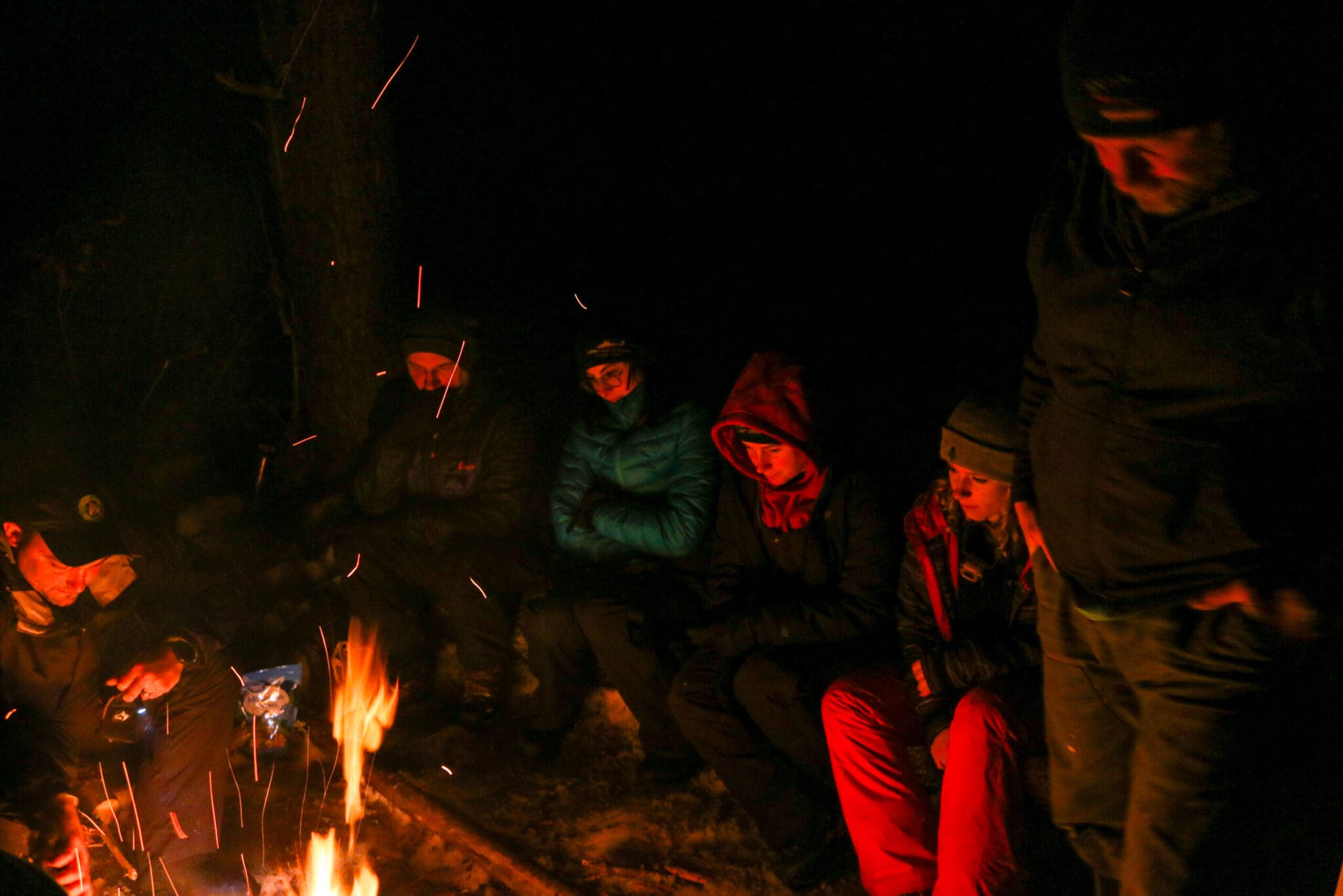 Participants huddle around the fire as the sun goes down.