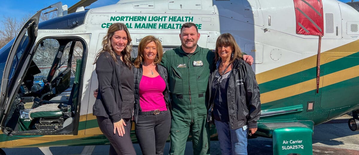A former patient stands in front of the helicopter with her mother, a flight nurse, and a flight paramedic.